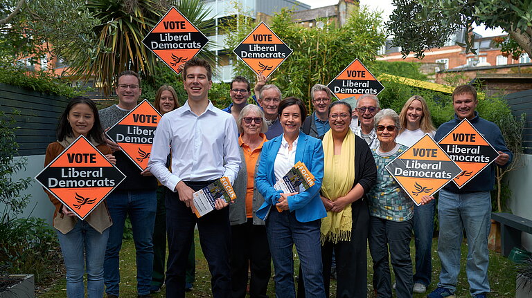 Lib Dem activists holding up Lib Dem stake boards